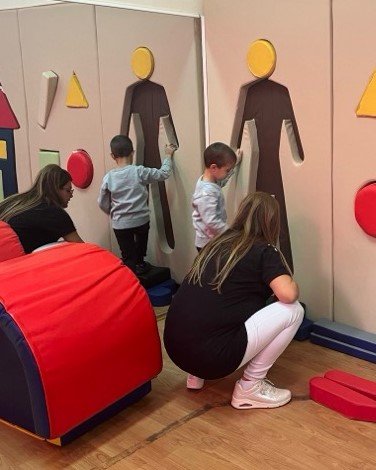 Children exploring a sensory wall with a teacher