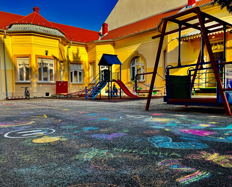The school’s yellow building and playground in Vršac