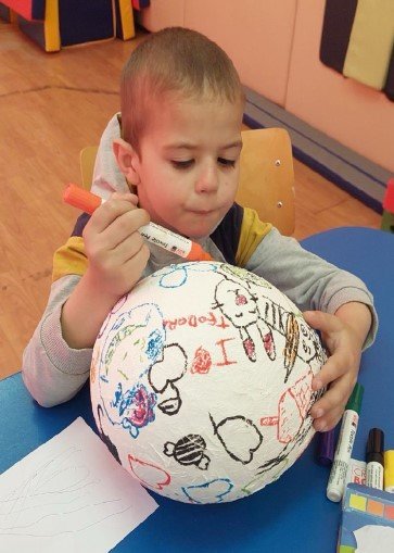 A child decorating a ball with markers