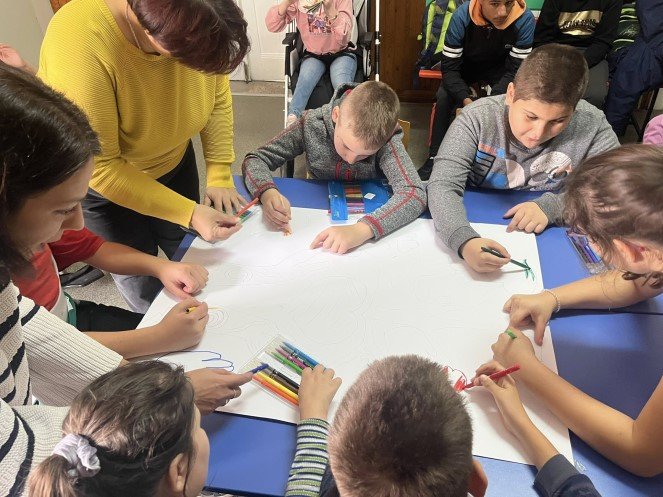 Primary school students and teachers working on a drawing together